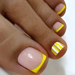 Close-up of yellow and white French tip toenail art with striped accent patterns