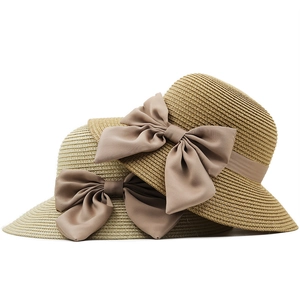 Dettaglio della trama in paglia intrecciata e grandi fiocchi di raso su cappelli