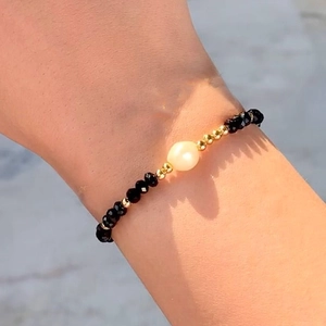 Detail of bohemian gold bead bracelet with black crystals and white pearl on wrist