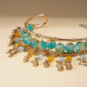 Detailed macro shot of bohemian wire-wrapped bangle with blue glass beads and gold charms