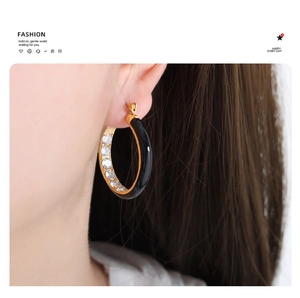 Close-up of model wearing C-shaped black enamel gold hoop earrings with inset crystals