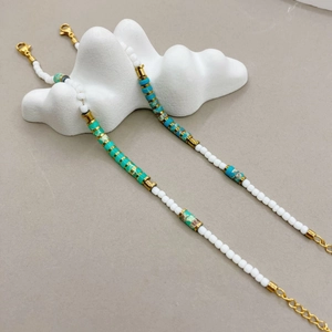 Minimalist beaded bracelet with turquoise stones and gold spacers on white cloud base