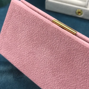 Pink granular texture travel jewelry box with golden metal clasp and layered storage