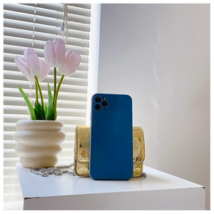 Matte dark blue phone case with triple camera setup next to gold crocodile pattern mini bag