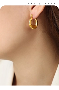 Close-up of model wearing gold-plated minimalist U-shaped geometric hoop earrings