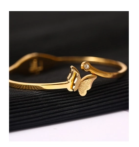 Macro shot of 18k gold butterfly open bracelet with polished wings and crystal detail