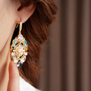 Detail view of vintage gold hollow earrings with colorful teardrop crystals on model