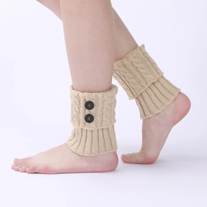 Close-up of beige cable knit leg warmers with vintage decorative buttons and ribbed texture