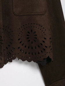 Détail de l'ourlet de veste en daim marron avec motifs floraux découpés au laser