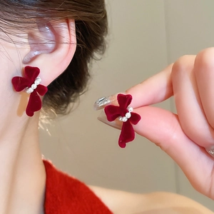 Detail of red flocked bow earrings with white pearl accents on high-quality silver studs