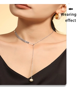 Detail of silver Y-shaped necklace with leaf charm and white pearl on model