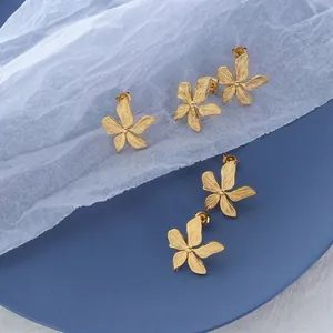Detailed macro view of 18k gold petal earrings featuring a textured brushed metal finish