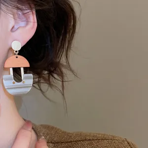 U-shaped geometric earrings with resin and wood pendants worn by a female model