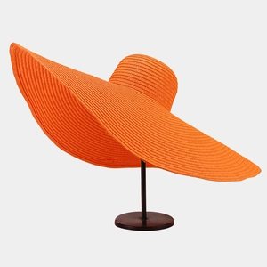Detail of wide wavy brim and dense spiral weave on bright orange straw sun hat