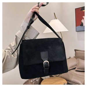 Minimalist black faux suede tote bag with gold buckle in a modern living room
