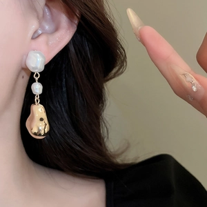 Gros plan de boucles d'oreilles baroques dorées avec perles blanches sur un mannequin