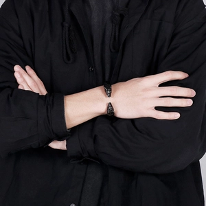 Détail d'un bracelet ouvert à tête de loup en acier inoxydable noir porté sur un poignet