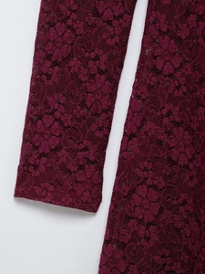 Detailed macro view of wine red floral lace fabric and cuff stitching on the dress