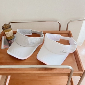 Detail of grey and white sun visors with pink piping and mountain embroidery on wooden cart