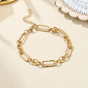 Macro detail of 18K gold-plated bracelet showing matte texture links and lobster clasp