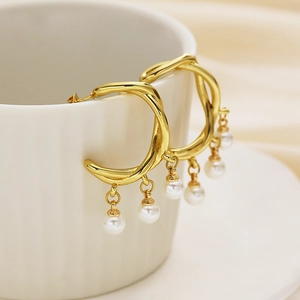 Close-up of gold-plated C-shaped twisted earrings with five white pearls hanging on a cup