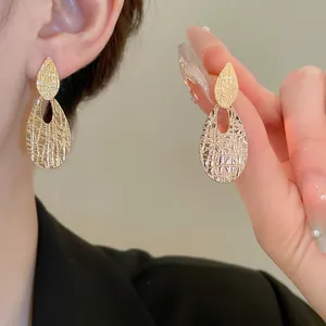 Exaggerated golden teardrop drop earrings with intricate hollow lattice texture
