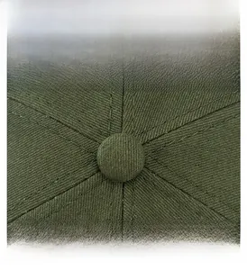 Macro shot of olive green cotton docker hat showing top button and reinforced stitching