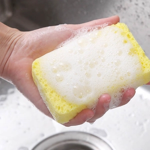 Yellow wood pulp sponge creating rich white foam for kitchen cleaning in a sink