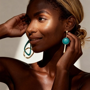 Close-up of geometric gold hoop and turquoise bead earrings on a fashion model