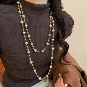 Close-up of double-layer champagne pearl and crystal bead necklace on brown sweater