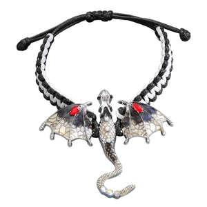 Detail van gevlochten drakenarmband met zilveren vleugels en fonkelende gekleurde steentjes
