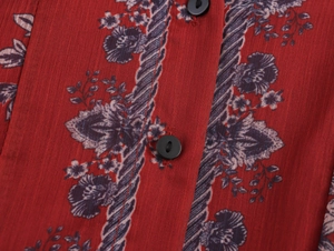 Close-up of red chiffon fabric with floral prints and a black button closure detail