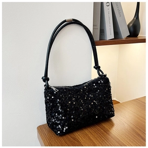 Close-up of sparkling black sequins on a baguette bag with silver zipper and leather strap