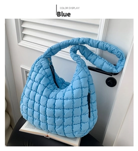Detail of blue quilted cloud bag on a chair showing glossy nylon texture and zipper