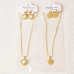 Detail of stainless steel jewelry sets featuring gold sunburst pearl and green agate pendants