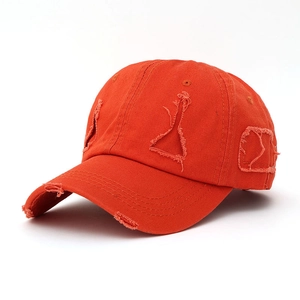 Detail of frayed orange cotton canvas baseball cap with distressed rip and vintage street style