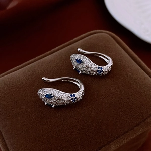Detail macro view of silver snake ear cuffs with blue zircon eyes on jewelry box display