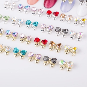 Detailed view of colorful bow-knot metal nail art charms with crystals in various shades