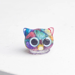 Macro view of colorful resin owl figurine with marble texture and large clear eyes