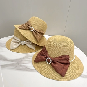 Elegant wide brim straw sun hats with pearl bow accents in multiple colors on marble background