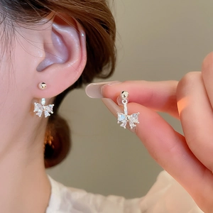 Detail showing bow-shaped silver earrings with sparkling cubic zirconia on model