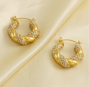 Close-up of 18K gold plated twisted hoop earrings with sparkling zircon inlay on satin