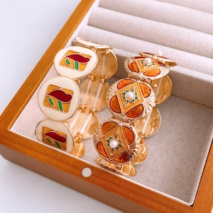 Detail of vintage enamel bangles with geometric patterns and pearls in a wooden box