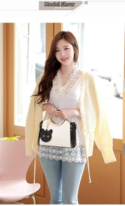 Detail view of contrast tote bag with golden circular handle and black cat charm