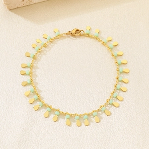Detailed close-up of golden teardrop charms and mint green beads on a delicate bracelet