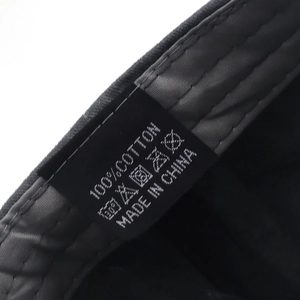 Detailed close-up of 100% cotton wash label and internal stitching on black cap