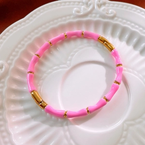 Dettaglio del braccialetto in smalto rosa stile bambù su un piatto di ceramica bianca