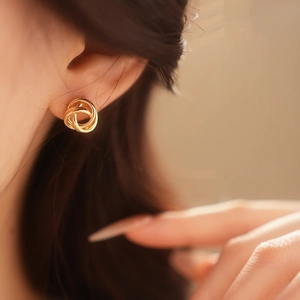 Gros plan sur une boucle d'oreille créole dorée torsadée pour un look chic et minimaliste