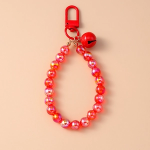 Detailed view of red beaded charm with glossy transparent beads and a small metal bell