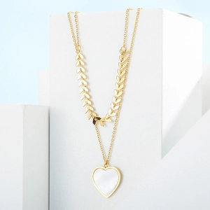 Detail of gold layered wheat chain with heart-shaped white shell pendant on stand